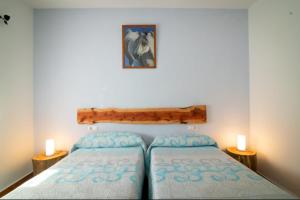 two beds in a bedroom with two candles on the wall at Hostal Papi in Zafrilla