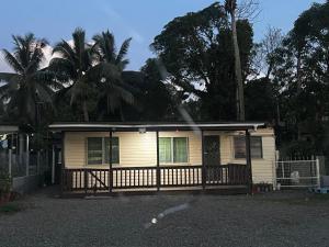 a small yellow house with a fence and palm trees at Aaqib Homestay in Suva