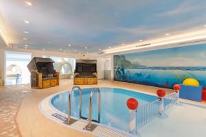 a large swimming pool in a room with a large painting at Familotel Kaiserhof - Families only in Berwang