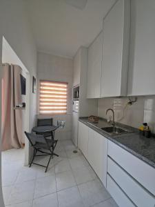 a kitchen with white cabinets and a table and a sink at Garça-Real 1 in Vale de Madeiros