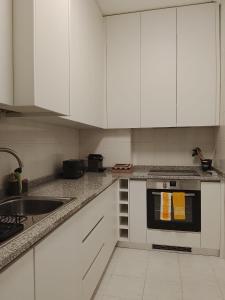a kitchen with white cabinets and a sink at Garça-Real 1 in Vale de Madeiros