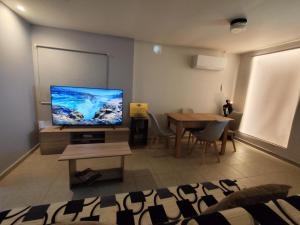 ein Wohnzimmer mit Flachbildfernseher und einem Tisch in der Unterkunft Aviator's Seafront Escape in Ágios Nikólaos