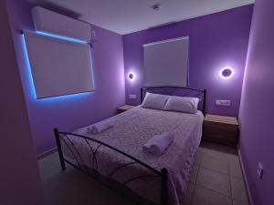 ein lila Schlafzimmer mit einem Bett und zwei Kissen darauf in der Unterkunft Aviator's Seafront Escape in Ágios Nikólaos
