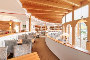 a restaurant with a long bar with chairs and tables at Familotel Kaiserhof - Families only in Berwang