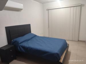 a bedroom with a bed with a blue blanket at casa confortabla y relajante con alberca y laguna in Monterrey