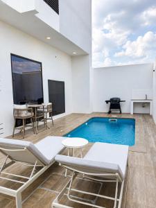 a pool in a room with chairs and a table at Ghosen Al Zaitoon chalet in Sayq
