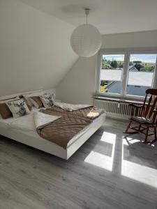 a bedroom with a bed and a chair and windows at Auszeit in Niedereschach
