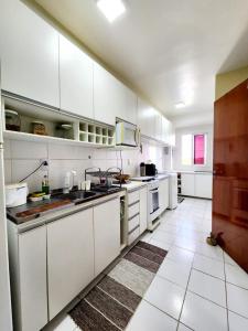 a large kitchen with white cabinets and white appliances at Apartamento Park Vinhais in São Luís