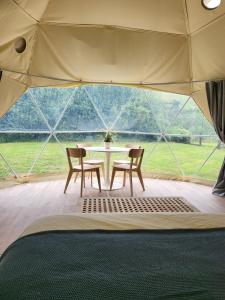 a tent with a table and chairs in front of a window at Pen-Y-Fan Glamping - Luxury Geodomes in Sennybridge