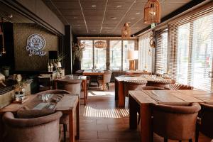 a restaurant with wooden tables and chairs and windows at Hotel La Boutique in Nijmegen