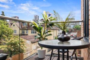 a table with a vase on a balcony with plants at Premium Apartment Steps from Wembley Park in London