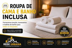 a stack of towels on a bed in a hotel room at Loft 10 com ar-condicionado da Rede Urbana in Indaiatuba