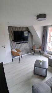 a living room with a couch and a tv on a wall at Haus Küstenglück in Neuharlingersiel