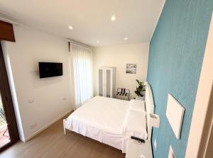 a bedroom with a white bed and a blue wall at B&B Il Tramonto in Capo dʼOrlando