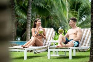 a man and a woman sitting in lawn chairs with drinks at The Sea Beach Residences - Arena Cam Ranh Resort in Cam Ranh International Airport