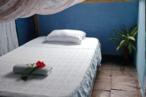 a bed with two pillows and a red flower on it at Perlas del cabo nuqui choco in Nuquí +9 photos
