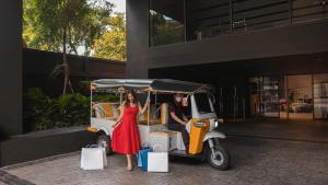 a woman in a red dress standing next to a golf cart at Oakwood Studios Sukhumvit Bangkok in Bangkok +40 photos