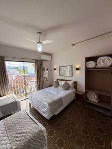 a hotel room with a bed and a window at Hotel Ze Maria Cambui in Cambuí