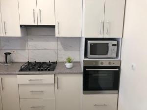 a white kitchen with a stove and a microwave at Light house in Ternopil +10 photos