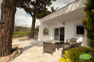 een patio met een tafel en stoelen naast een boom bij Bungalows Papalus - Golf Lloret - in Lloret de Mar