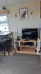 a living room with a television and a table with a chair at ScotThistle in Kirkcowan