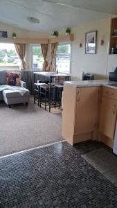 a living room with a couch and a table and a kitchen at ScotThistle in Kirkcowan