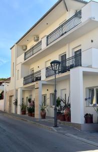 a white apartment building with potted plants on the street at Apartments & Studios Dalmatino in Vodice