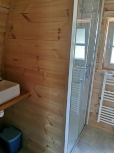 a shower in a bathroom with a wooden wall at La Cabane MIMOSA in Saint-Malo-du-Bois