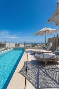 a swimming pool with chairs and umbrellas on a building at Lemar Luxury Apartments in Hersonissos