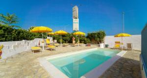 a swimming pool with yellow umbrellas and tables and chairs at Mapo Village Plaia in Villanova di Ostuni