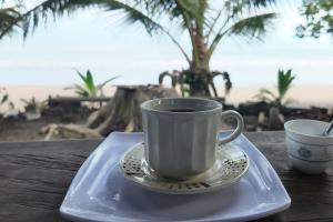 a cup of coffee sitting on a plate on a table at Perlas del cabo nuqui choco in Nuquí