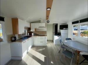 a kitchen with white cabinets and a table with chairs at Bungalow à la mer in Villeneuve-en-Retz