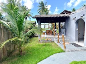 a house with a palm tree in the yard at GREY HOUSE - frente para o mar em Carapibus in Conde