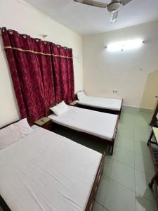 a room with three beds and a red curtain at Adeel hotel & Restaurant Mianwali in Bānda Arāīyān