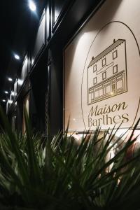 a sign for a restaurant with a plant in the foreground at Maison Barthes Suites B&B in Baraqueville