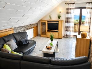 a living room with a black leather couch and a tv at Ferienwohnung Frischkorn in Steinau an der Straße