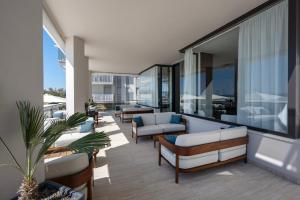 an apartment patio with couches and chairs on a balcony at Hotel Byron Bellavista in Lido di Jesolo