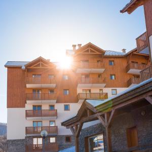 a building with the sun shining behind it at Les Gentianes by Actisource in Puy-Saint-Vincent