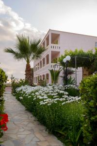 a white building with a palm tree and white flowers at Hotel Kiklamino in Kalamaki Heraklion