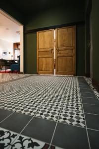 a room with a black and white tile floor and wooden doors at Maison Barthes Suites B&B in Baraqueville