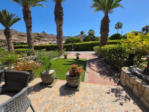 a patio with palm trees and a garden with flowers at Villa Torbellino, Diseño, Privacidad y Confort in La Playa de Tauro