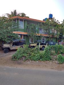 a green building with vehicles parked in front of it at Wildways Mudumalai Homestay in Masinagudi