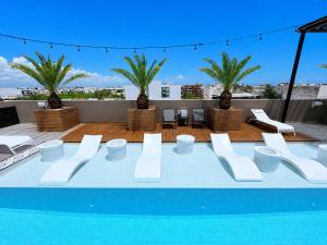 a pool with white chairs and a table on a roof at MARQUEE Playa Hotel in Playa del Carmen