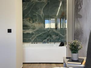a bathroom with a white tub and a marble wall at Flower Beach Helgueras 2 - 6092 in Noja