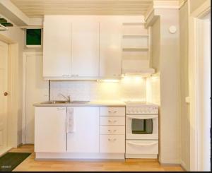 a kitchen with white cabinets and a sink and a stove at Rautatien ullakkohuoneisto in Karkkila +13 photos