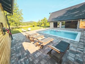 a swimming pool with chaise lounges and a patioitures at Senjska Villa in Josipdol