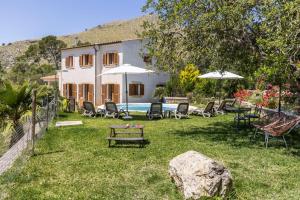 a house with a yard with chairs and umbrellas at Villa Maria in Port de Pollensa