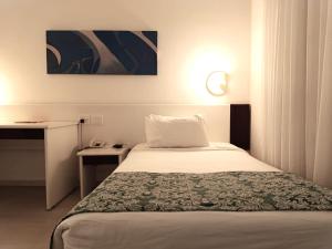 a hotel room with a bed and a desk at Boulevard Plaza in Belo Horizonte