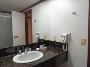 a bathroom with a sink and a large mirror at Boulevard Plaza in Belo Horizonte
