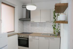 a white kitchen with a sink and a stove at Between Pines&Sea Strunjan in Strunjan